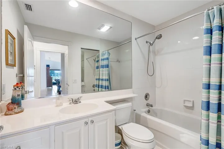 Bathroom featuring shower / bathtub combination with curtain, toilet, and vanity