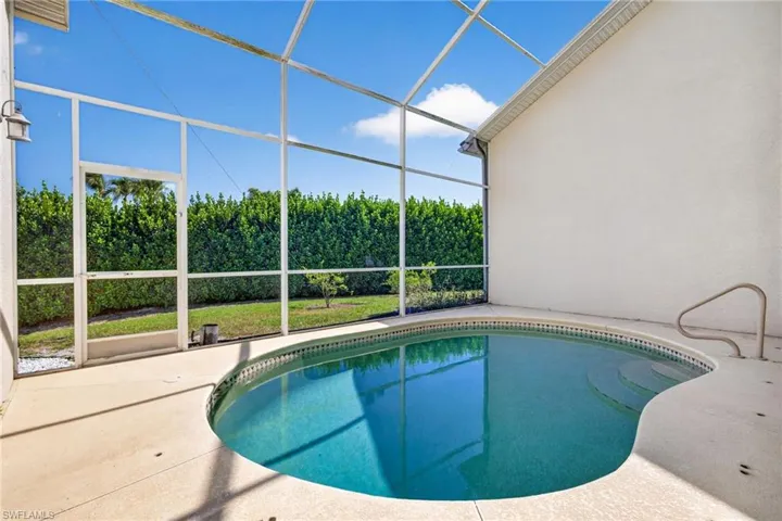 Screened-in outdoor pool featuring a contoured shape, integrated steps, and a handrail