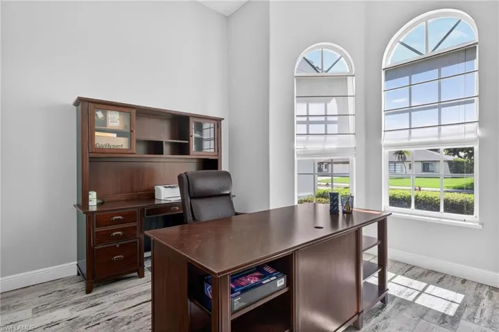 Room featuring two arched windows, wood-finish flooring, and white baseboards