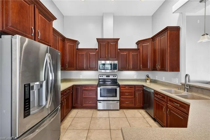 Kitchen featuring U-shaped counter space, recessed lighting, stainless steel appliances, dark wood cabinetry, and tile flooring