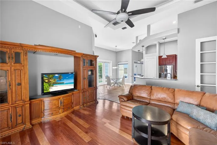 Living area featuring wood-finish flooring, vaulted ceilings, and a modern ceiling fan