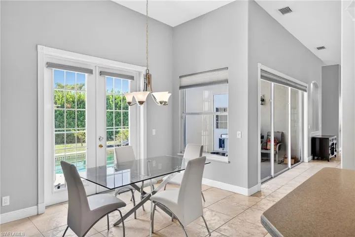 Dining area featuring high ceilings, tile flooring, and glass-paneled French doors leading to the exterior