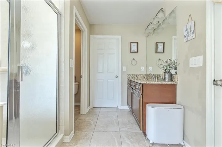 Bathroom featuring baseboards, toilet, vanity, tile patterned flooring, and a stall shower