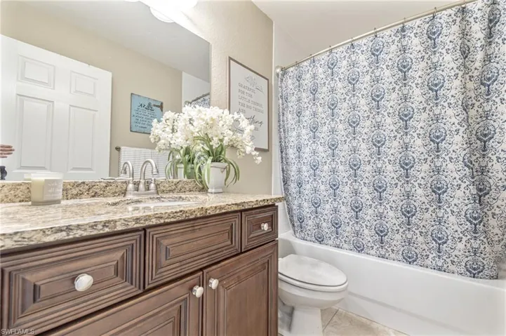 Full bath featuring toilet, vanity, tile patterned flooring, and shower / tub combo with curtain