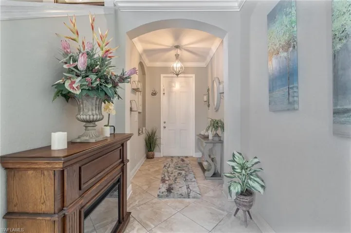 Doorway with crown molding, baseboards, and arched walkways