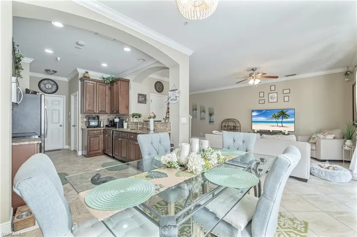 Dining room with arched walkways, light tile patterned floors, a ceiling fan, and crown molding