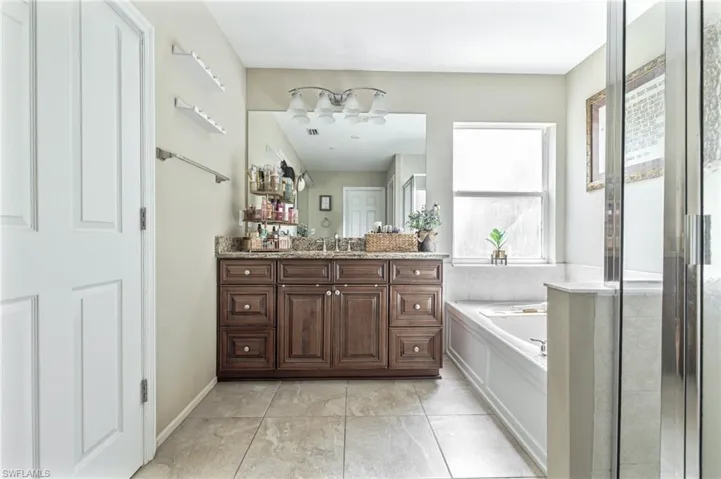 Bathroom with tile patterned flooring, vanity, an enclosed shower, and a garden tub