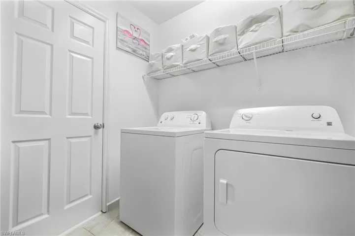 Laundry room featuring washer and clothes dryer, light tile patterned floors, and laundry area