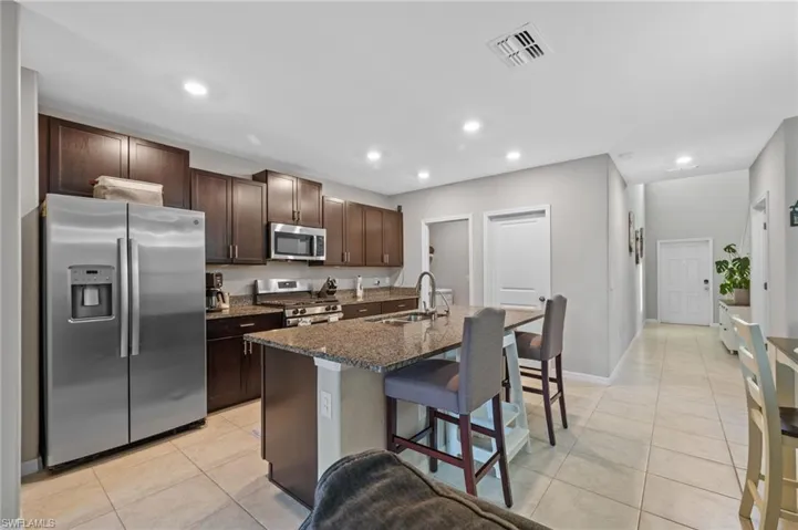 Kitchen featuring appliances with stainless steel finishes, a breakfast bar, dark brown cabinets, sink, and a center island with sink