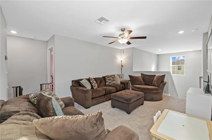 Living room with ceiling fan and light colored carpet