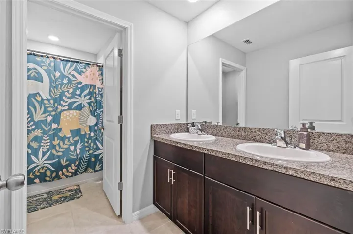 Bathroom with tile patterned flooring, vanity, and shower / tub combo with curtain