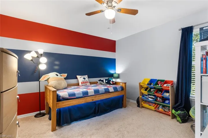 Carpeted bedroom with a ceiling fan and baseboards