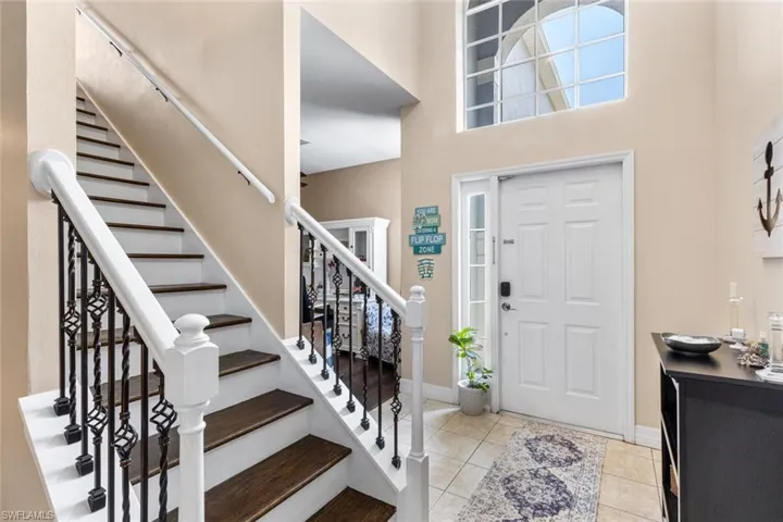 Tiled entryway with stairway and a towering ceiling