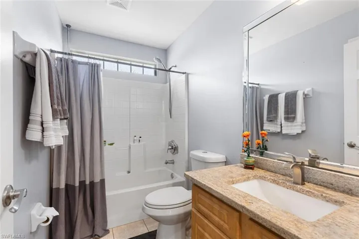 Full bathroom with shower / bath combo, vanity, and tile patterned flooring