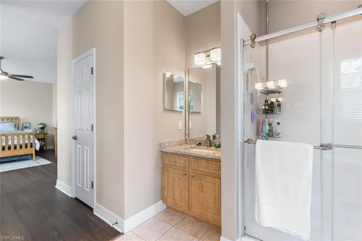 Full bathroom with ensuite bath, vanity, a stall shower, and ceiling fan