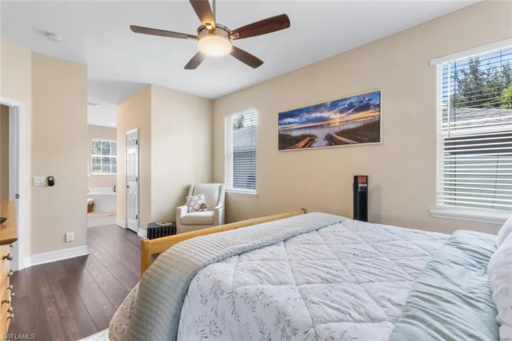 Bedroom featuring hardwood / wood-style floors, ceiling fan, and ensuite bath