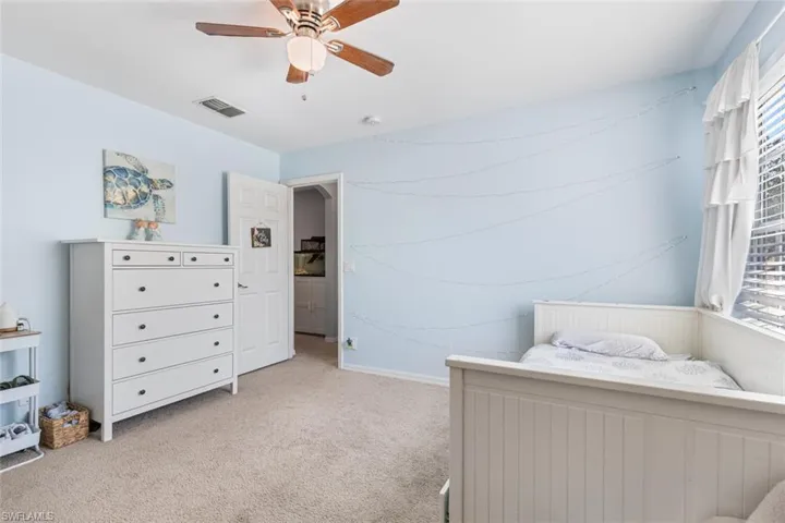Bedroom with light colored carpet, multiple windows, and ceiling fan