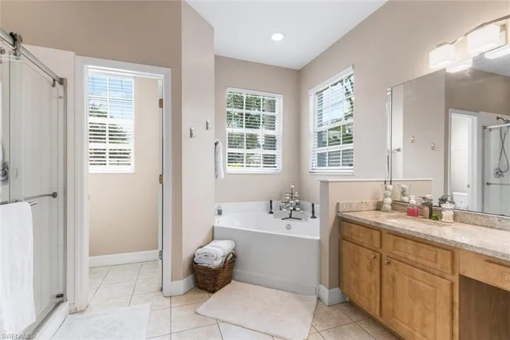 Full bath featuring vanity, a shower stall, a garden tub, and tile patterned floors
