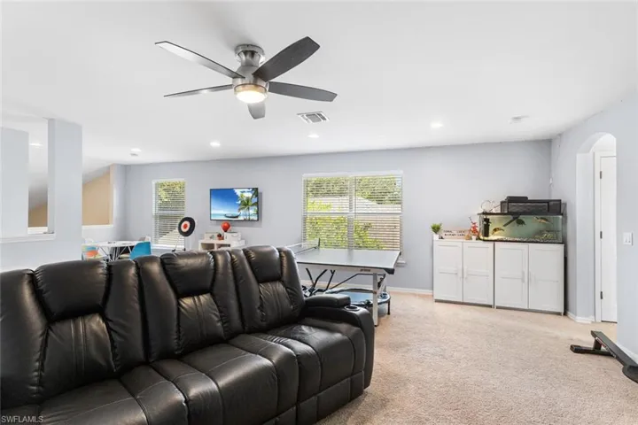 Living room with arched walkways, a ceiling fan, light carpet, and recessed lighting