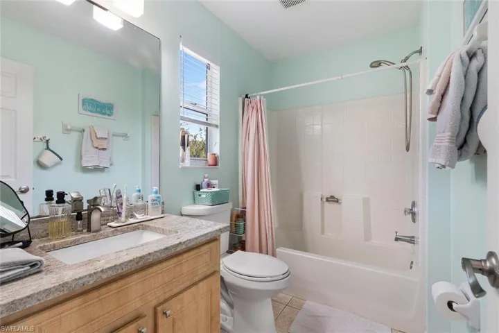Full bathroom featuring vanity, shower / bath combo with shower curtain, and tile patterned flooring
