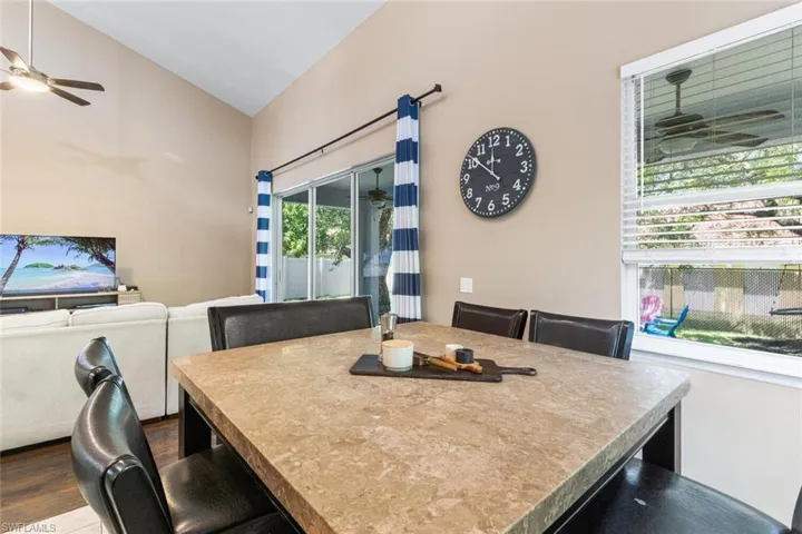 Dining area featuring ceiling fan, lofted ceiling, and dark wood-style flooring