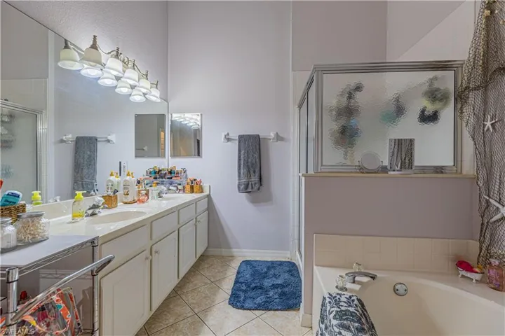 Bathroom with tile patterned flooring, vanity, and plus walk in shower