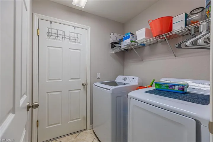 Washroom featuring light tile patterned floors and washer and clothes dryer