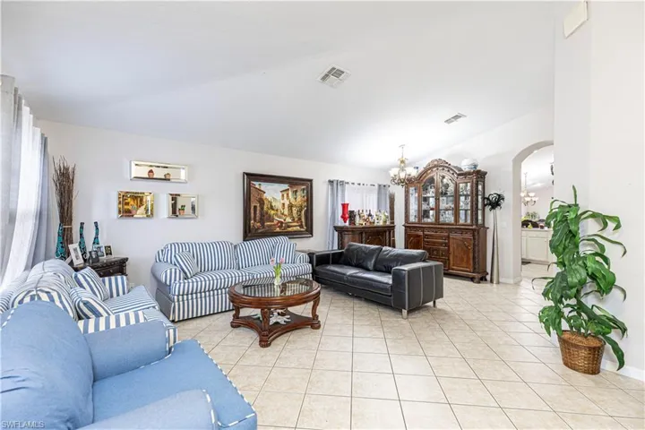 Living room featuring lofted ceiling, a chandelier, and light tile patterned flooring