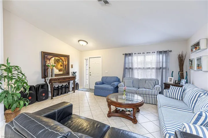 Tiled living room featuring vaulted ceiling