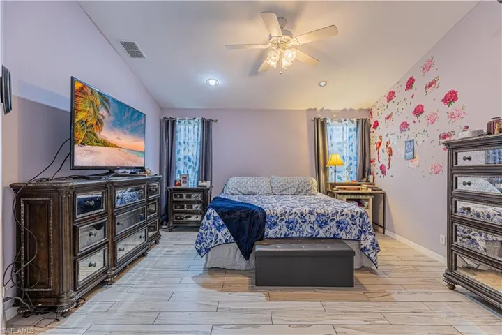 Bedroom featuring ceiling fan, multiple windows, and light hardwood / wood-style floors