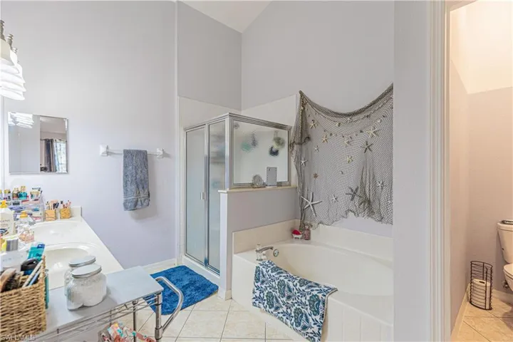 Full bathroom featuring vanity, toilet, plus walk in shower, and tile patterned flooring