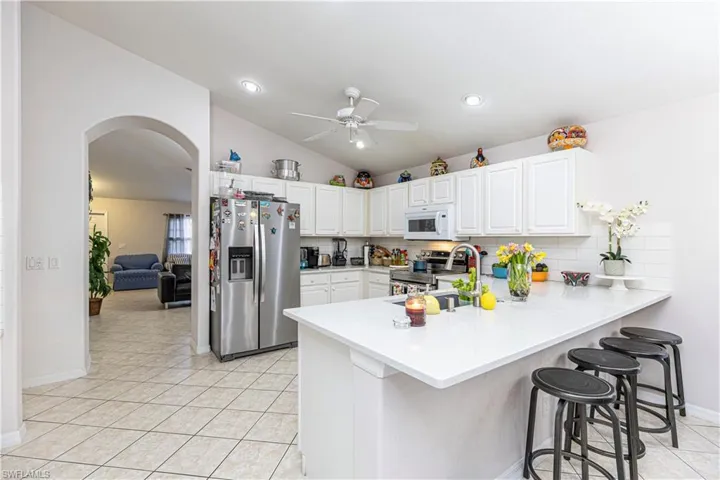 Kitchen with appliances with stainless steel finishes, a breakfast bar, kitchen peninsula, lofted ceiling, and ceiling fan