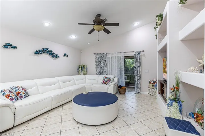 Tiled living room with vaulted ceiling and ceiling fan