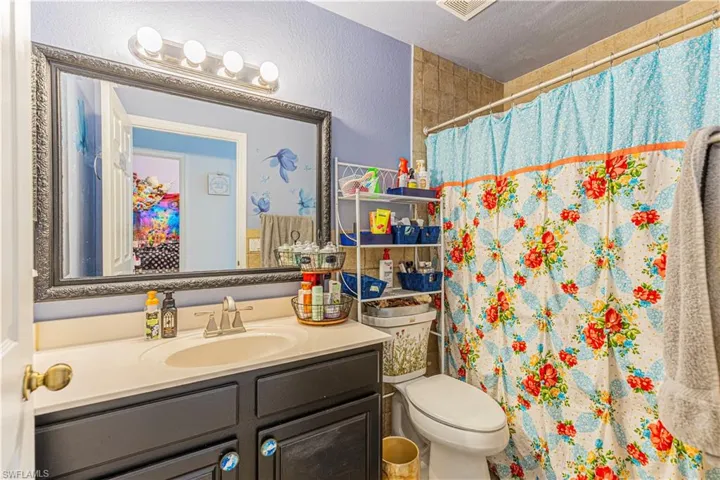 Bathroom with vanity, toilet, a shower with curtain, and a textured ceiling