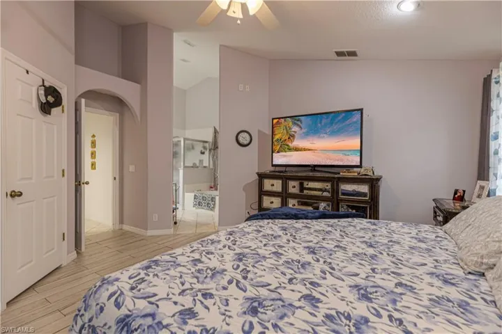 Bedroom featuring lofted ceiling, ceiling fan, ensuite bathroom, and light hardwood / wood-style floors