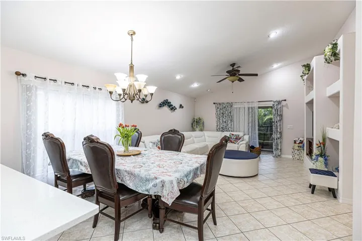 Tiled dining space featuring lofted ceiling and ceiling fan with notable chandelier