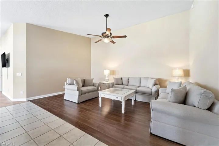 Living room with wood finished floors, a textured ceiling, a ceiling fan, and lofted ceiling