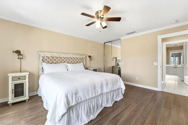 Bedroom featuring wood finished floors, crown molding, ceiling fan, and a closet