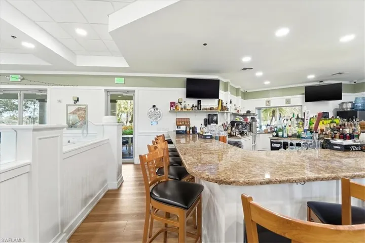 Kitchen featuring a kitchen breakfast bar, light stone countertops, white cabinets, recessed lighting, and open shelves