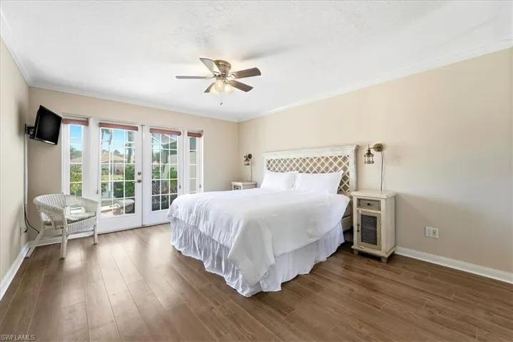 Bedroom featuring access to exterior, french doors, wood finished floors, ornamental molding, and ceiling fan