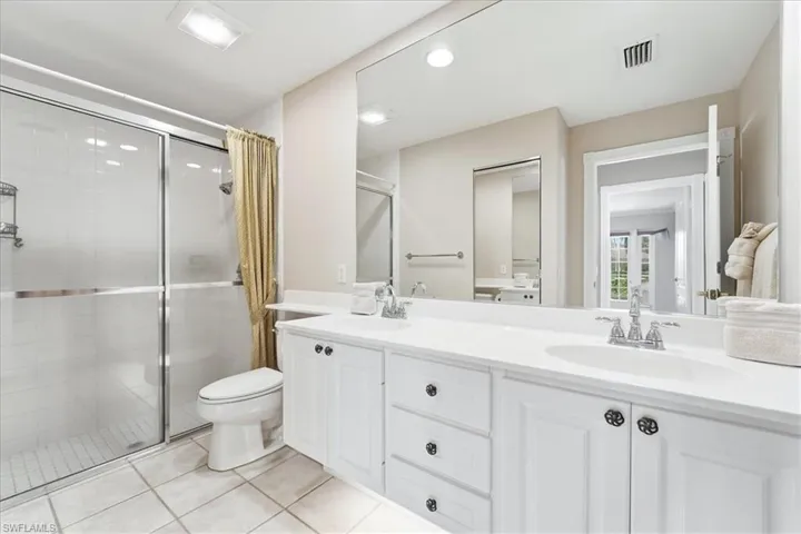 Full bathroom featuring a stall shower, double vanity, and light tile patterned floors