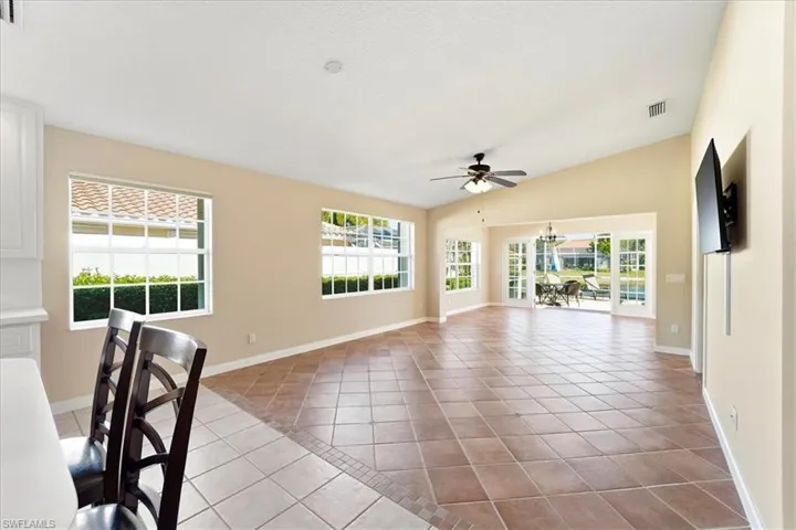 Unfurnished living room featuring lofted ceiling, light tile patterned floors, and ceiling fan