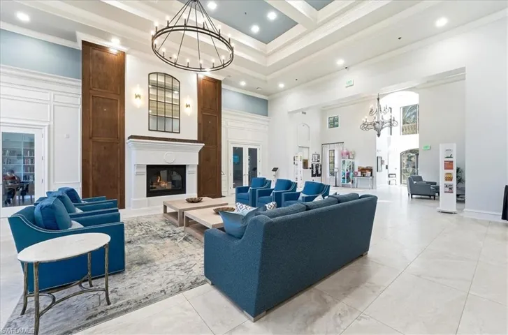 Living area featuring a chandelier, a high ceiling, a fireplace, recessed lighting, and crown molding
