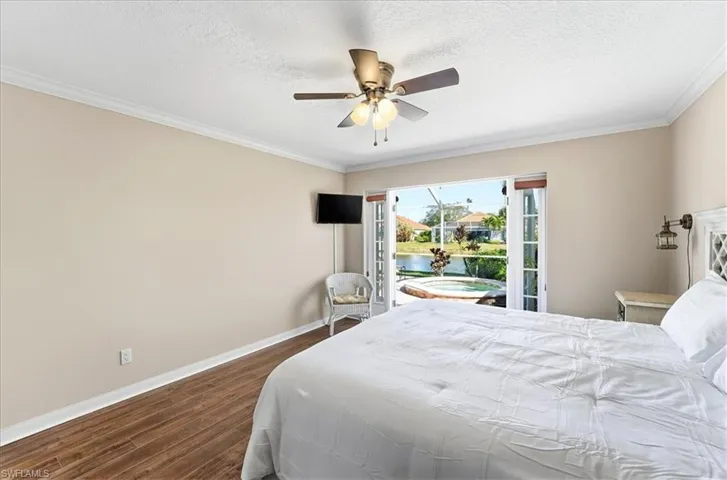 Bedroom featuring dark wood finished floors, ceiling fan, a textured ceiling, ornamental molding, and access to outside