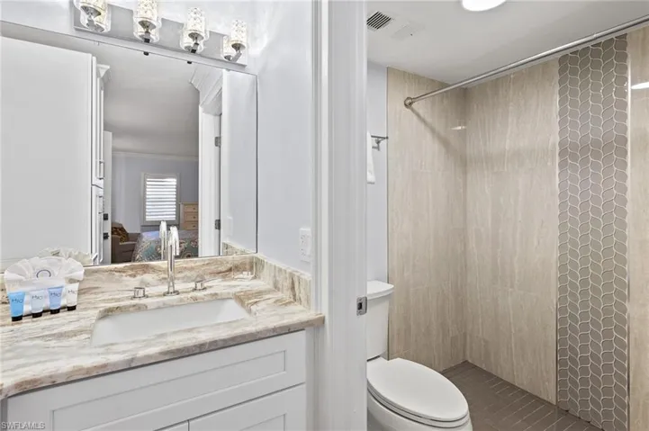 Bathroom featuring ornamental molding, a tile shower, vanity, and toilet