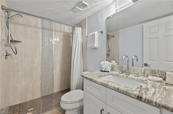 Bathroom with a shower with curtain, vanity, and toilet