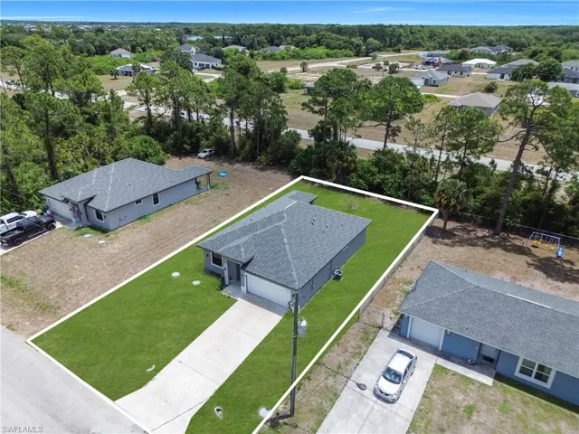 Modern single-story residence featuring a gray exterior, a dark gray shingle roof, a two-car garage, an elongated concrete driveway, and a manicured green lawn