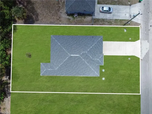 Expansive lot featuring a newly constructed home with a dark shingle roof, a concrete driveway, and ample green space
