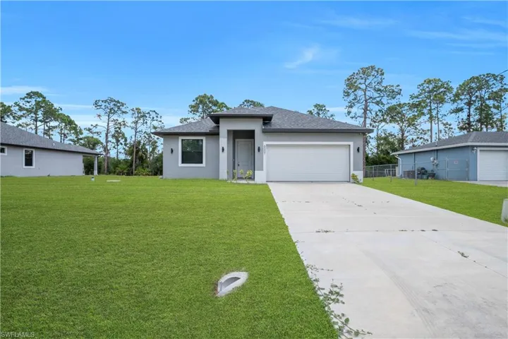 Modern single-story residence featuring a two-car garage, a gray exterior with white trim, and a concrete driveway