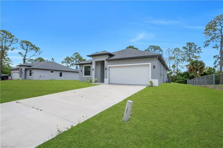 Contemporary single-story residence featuring a neutral grey stucco exterior, attached garage, and a concrete driveway
